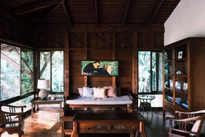 A wooden room with a bed, a bookshelf, and a painting on the wall.