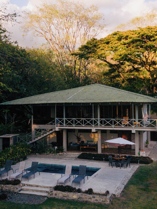 A building with a covered patio, outdoor seating, and a swimming pool.