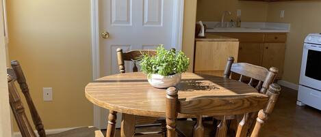 A dining area with a round wooden table, six chairs, and a potted plant.