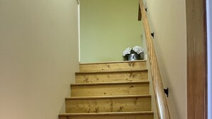 A wooden staircase with a handrail, leading to a landing with a potted plant.