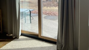 A room with a large sliding glass door leading to an outdoor area with a view of a mountainous landscape.