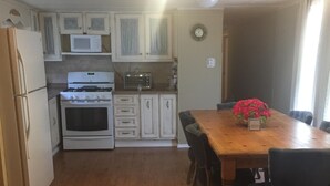 A compact kitchen with white appliances, a dining table with chairs, and a small decorative plant. - Sanders Island View Beach Home only 3 blocks to the beach!  (Kingston)