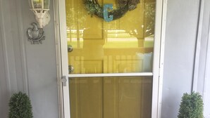 A front door with a glass panel, a welcome mat, and two potted plants. - Sanders Island View Beach Home only 3 blocks to the beach!  (Kingston)