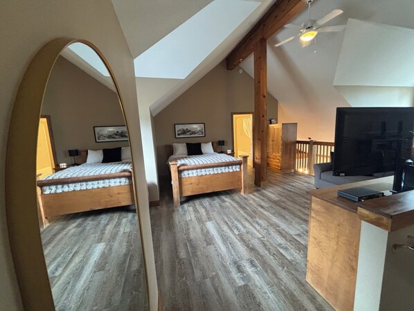 A bedroom with two beds, a TV, and a wooden ceiling.