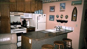 A kitchen with a central island, wooden stools, a refrigerator, a stove, and a microwave. - Waterfront Condo located on the shores of Lake Erie in Port Clinton, Ohio. (Port Clinton)