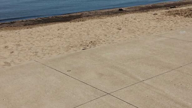 A beach with a concrete walkway and a blue chair. - Waterfront Condo located on the shores of Lake Erie in Port Clinton, Ohio. (Port Clinton)