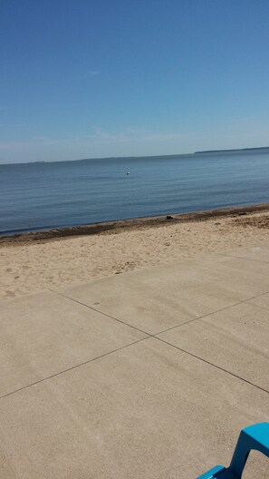 Une plage avec une promenade en béton et une chaise bleue.
