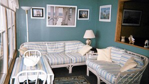 A room with a striped sofa, a small table, and a chair. There are framed pictures on the wall and a lamp on the table. - Waterfront Condo located on the shores of Lake Erie in Port Clinton, Ohio. (Port Clinton)