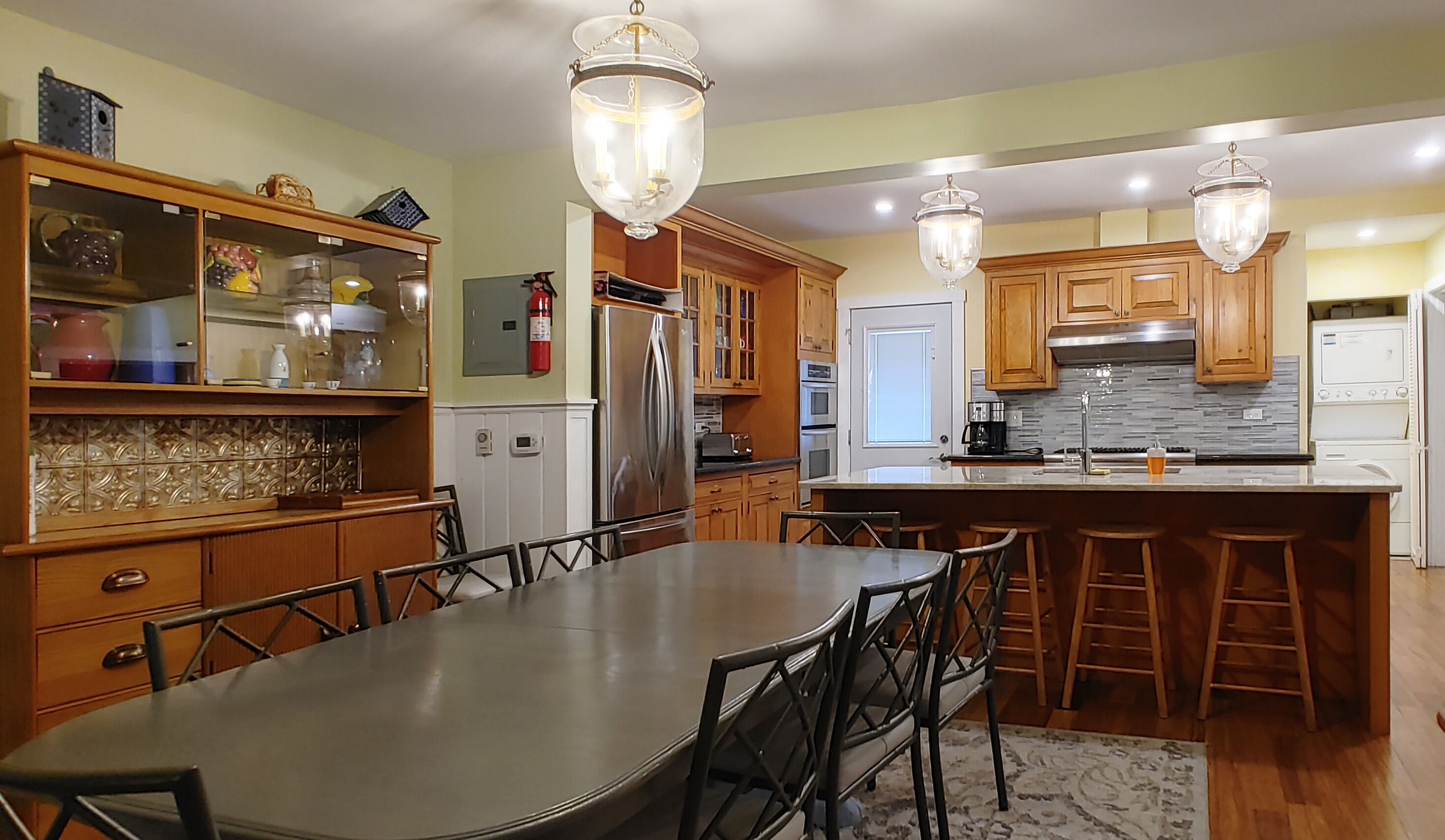 A modern kitchen with wooden cabinets, a stainless steel refrigerator, and a large island with stools.