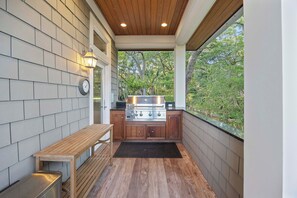 A covered outdoor kitchen area with a built-in stove, wooden bench, and a view of the surrounding greenery.
