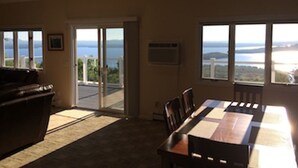A room with a dining table, chairs, a sofa, and a view of the sea through large windows. - Ski Gunstock 3 minutes away then relax overlooking lakeWinnipesaukee







mile (GILFORD)