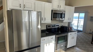 A modern kitchen with stainless steel appliances, white cabinets, and a large window offering a view. - Ski Gunstock 3 minutes away then relax overlooking lakeWinnipesaukee







mile (GILFORD)