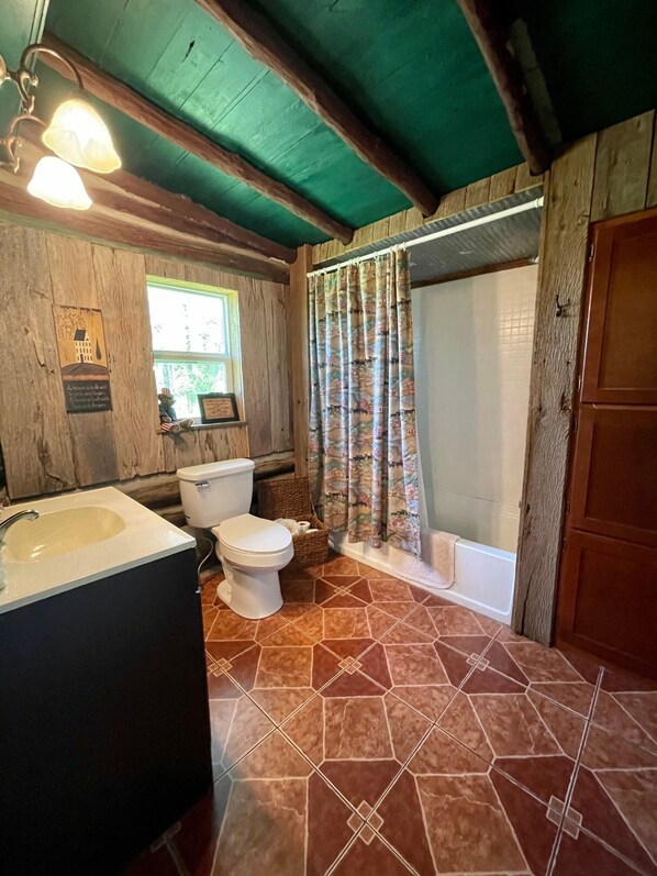 Ein Badezimmer mit Holzvertäfelung, einem Waschbecken, einer Toilette und einer Duschkabine.