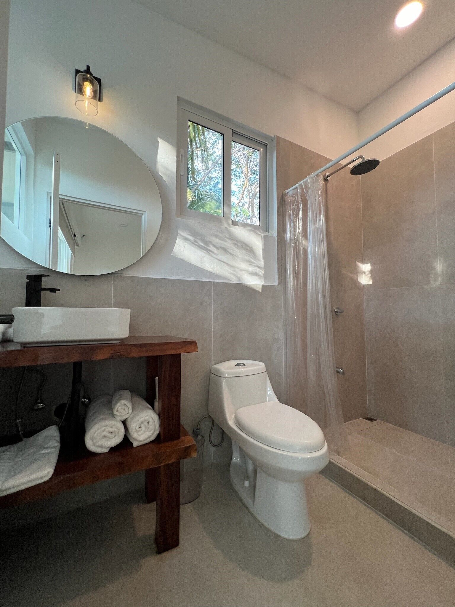 A modern bathroom with a toilet, a sink, a mirror, and a shower.