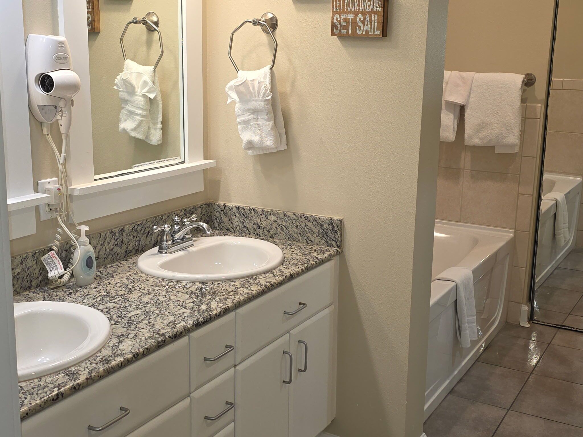A bathroom with two sinks, a hairdryer, and a glass shower enclosure.