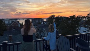 Two people on a balcony overlooking a sunset with a view of a marina and residential buildings. - Your search ends here! (Newport)