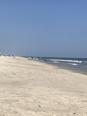 Enjoy a serene beach experience with a wide sandy shore and calm ocean.