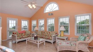 Relax in this spacious living room with a high ceiling, arched window, and comfortable seating for two.