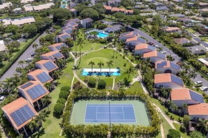 Ein Wohngebiet mit mehreren Häusern, einem Tennisplatz und Solaranlagen auf den Dächern.