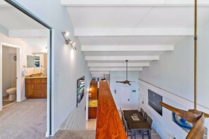 A modern interior with a kitchen, dining area, and a hallway leading to a bathroom.
