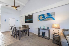 A dining area with a table and chairs, a ceiling fan, a wall with a starry night painting, and a console table with decorative items.