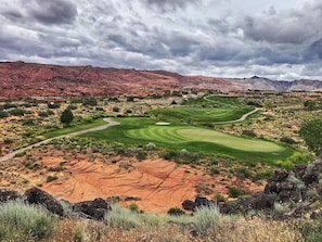 A golf course with a desert landscape, including red rock formations and sparse vegetation.