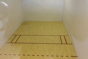 A squash court with a wooden floor and white walls.