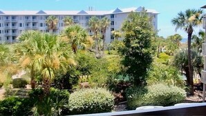 Un hotel con fachada blanca, varios balcones y abundante vegetación, incluyendo palmeras.