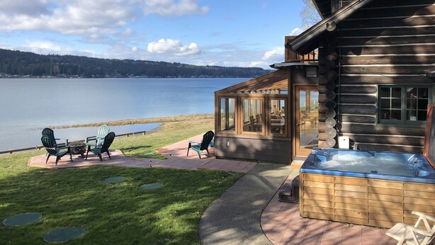 Un chalet en rondins doté d’un bain à remous et d’un espace extérieur aménagé près d’un lac.