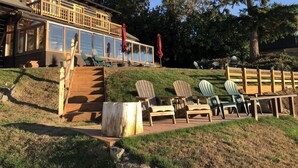 Un chalet doté d’une terrasse, de meubles de jardin et d’une grande fenêtre donnant sur le paysage.