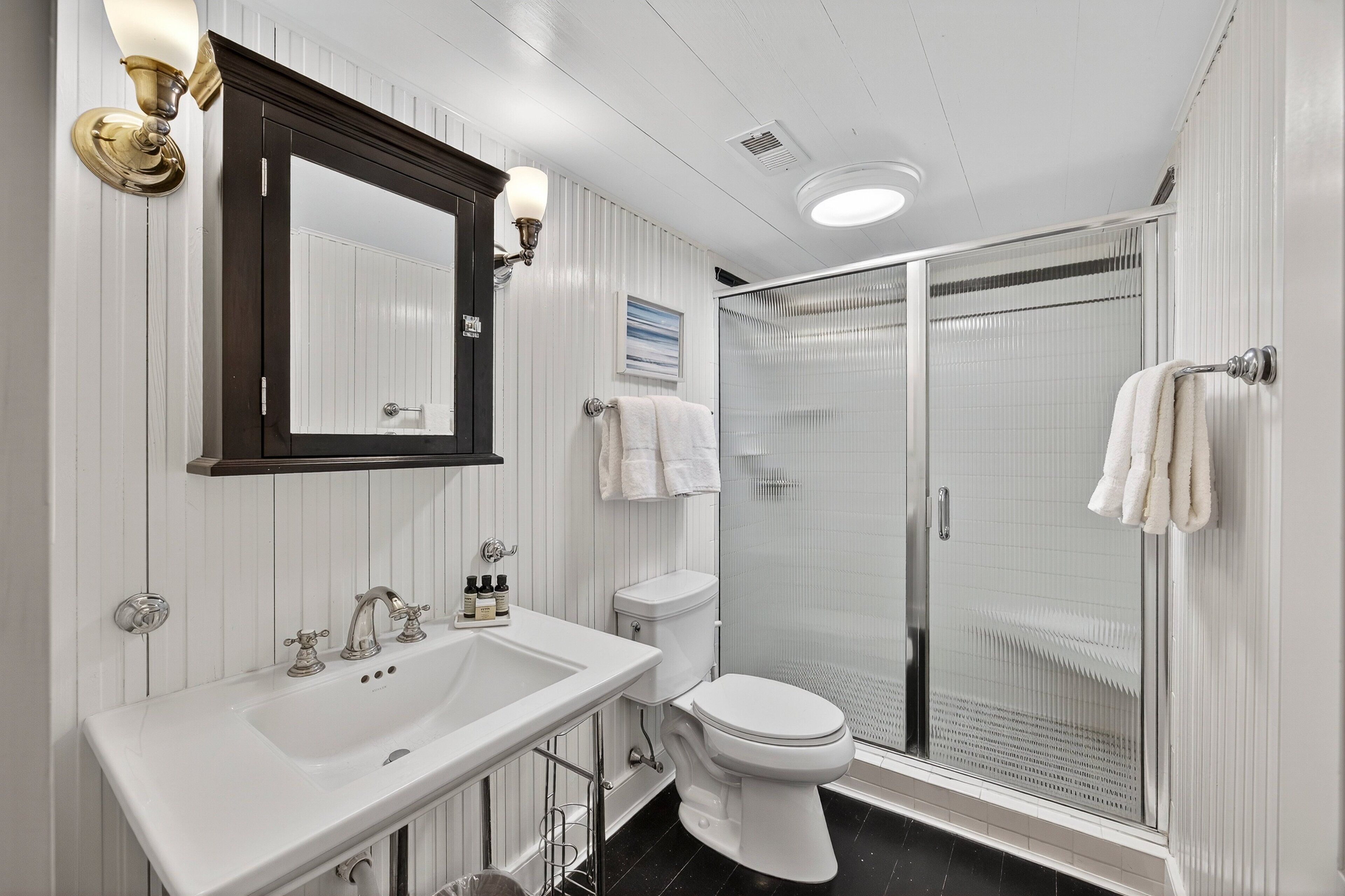 A bathroom with a white sink, a toilet, and a glass-enclosed shower.