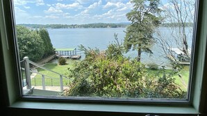 A view from a window overlooking a lake with a dock, grassy area, and trees.