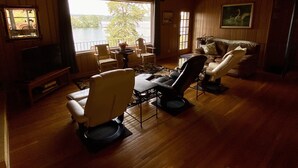 A cozy living room with wooden floors, a ceiling fan, and a large window overlooking a lake.