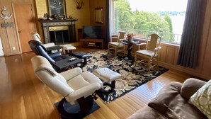 A cozy living room with a fireplace, a television, and a view of the outdoors.
