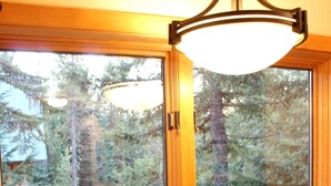 Una cocina con un lavamanos doble, una ventana con vista a un bosque y un cartel que dice 'LET IT SNOW' en el alféizar.