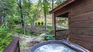 A hot tub in a wooded area with a wooden cabin and a picnic table. - Mountain serenity close to hiking, rafting, fishing and kayaking.  "Coyote Song" (Topton)