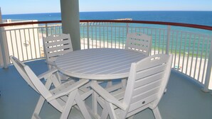Un balcon avec une table et des chaises blanches, donnant sur l’océan.