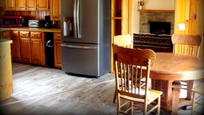 A kitchen with wooden cabinets, a stainless steel refrigerator, a microwave, and a dining table with chairs.