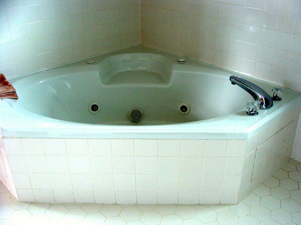 Una bañera rectangular con un solo grifo, un desagüe y un vaso pequeño al lado.