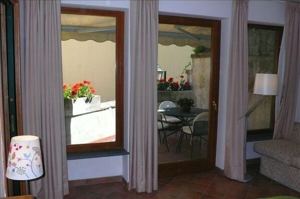 A room with a view of a balcony, a dining area, and a sofa.