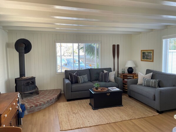 A living room with a fireplace, two sofas, a coffee table, and a view of a pool outside.