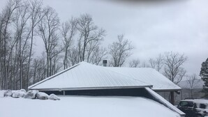 A snow-covered building with a sloped roof, surrounded by trees and a parked vehicle. - Make your reservation fast as inquiries are coming in daily.  (Redford)