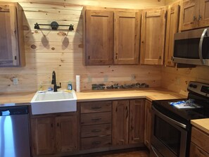 A kitchen with wooden cabinets, a stainless steel refrigerator, a sink, and a microwave. - Make your reservation fast as inquiries are coming in daily.  (Redford)