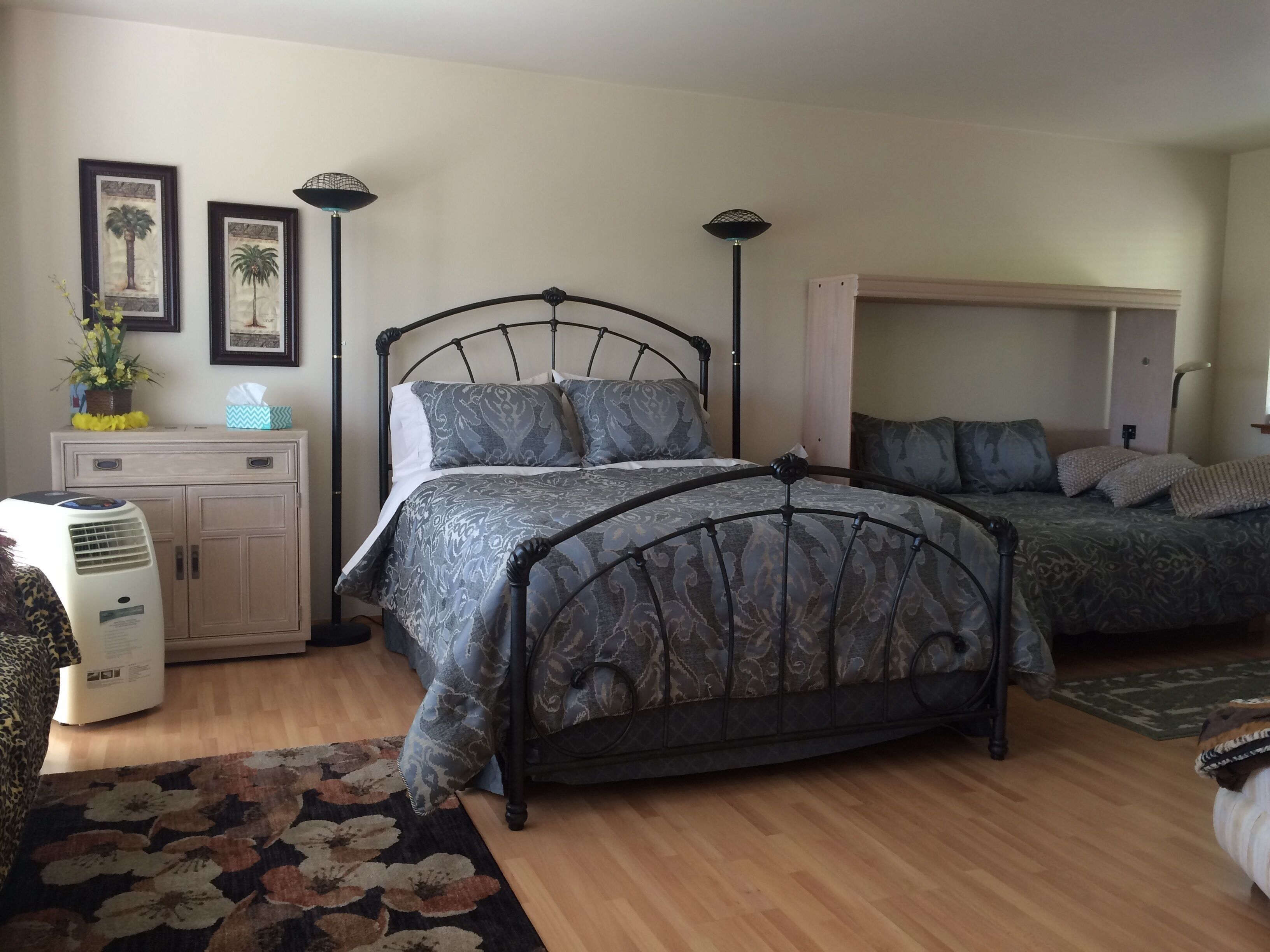 Un dormitorio con cama, mesitas de noche, lámpara, calefactor y alfombra.