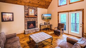 A cozy living room with a fireplace, wooden flooring, and comfortable seating. - Amazing Cabin w/Firepit, Gametable, Hot Tub, Wifi, Cable (Banner Elk)