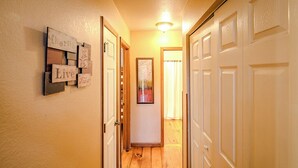 A hallway with wooden flooring, white doors, and a wall-mounted sign with the words "Cherish Live." - Amazing Cabin w/Firepit, Gametable, Hot Tub, Wifi, Cable (Banner Elk)