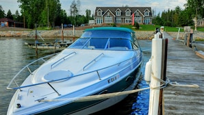 A speedboat docked at a wooden pier with a house in the background. - Waterfront Home With Swimming Pond - 61  - 5 star reviews  FREE 2 HOUR PONTOON (Sturgeon Bay)