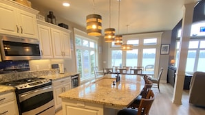 A modern kitchen with white cabinetry, stainless steel appliances, and a granite countertop. - Waterfront Home With Swimming Pond - 61  - 5 star reviews  FREE 2 HOUR PONTOON (Sturgeon Bay)