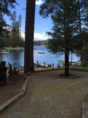 A lakeside view with a dock, picnic tables, and a stone bench area. - A private dock, secluded cove, large deck, lots of parking,  amazing lake view. (Bass Lake)