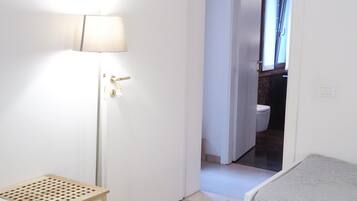 Une chambre avec deux lits, une lampe sur pied et une porte donnant sur une salle de bain.